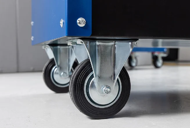 Nahaufnahme zweier kleiner Lenkrollen unter dem blauen Werkzeugrollwagen.